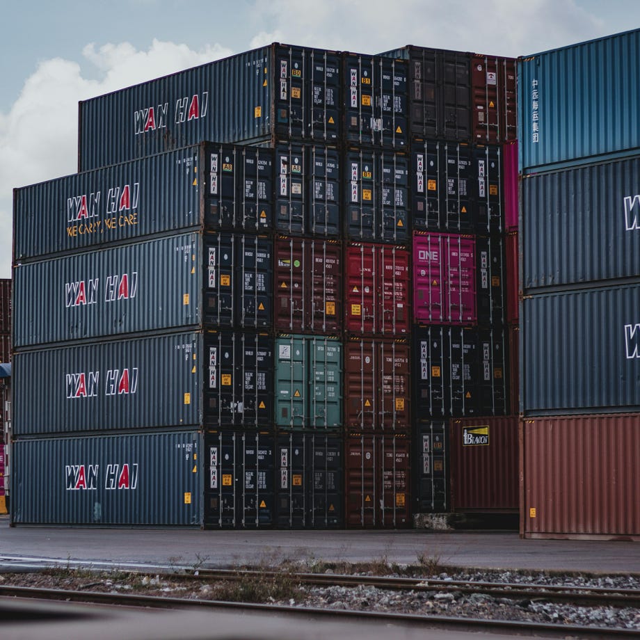 High vertical stack of cargo containers at a port, symbolizing global logistics.